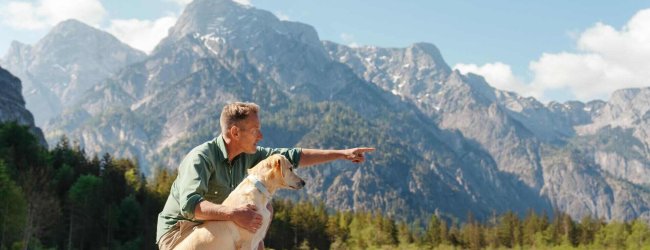 A man with a dog that's wearing a Tractive GPS tracker